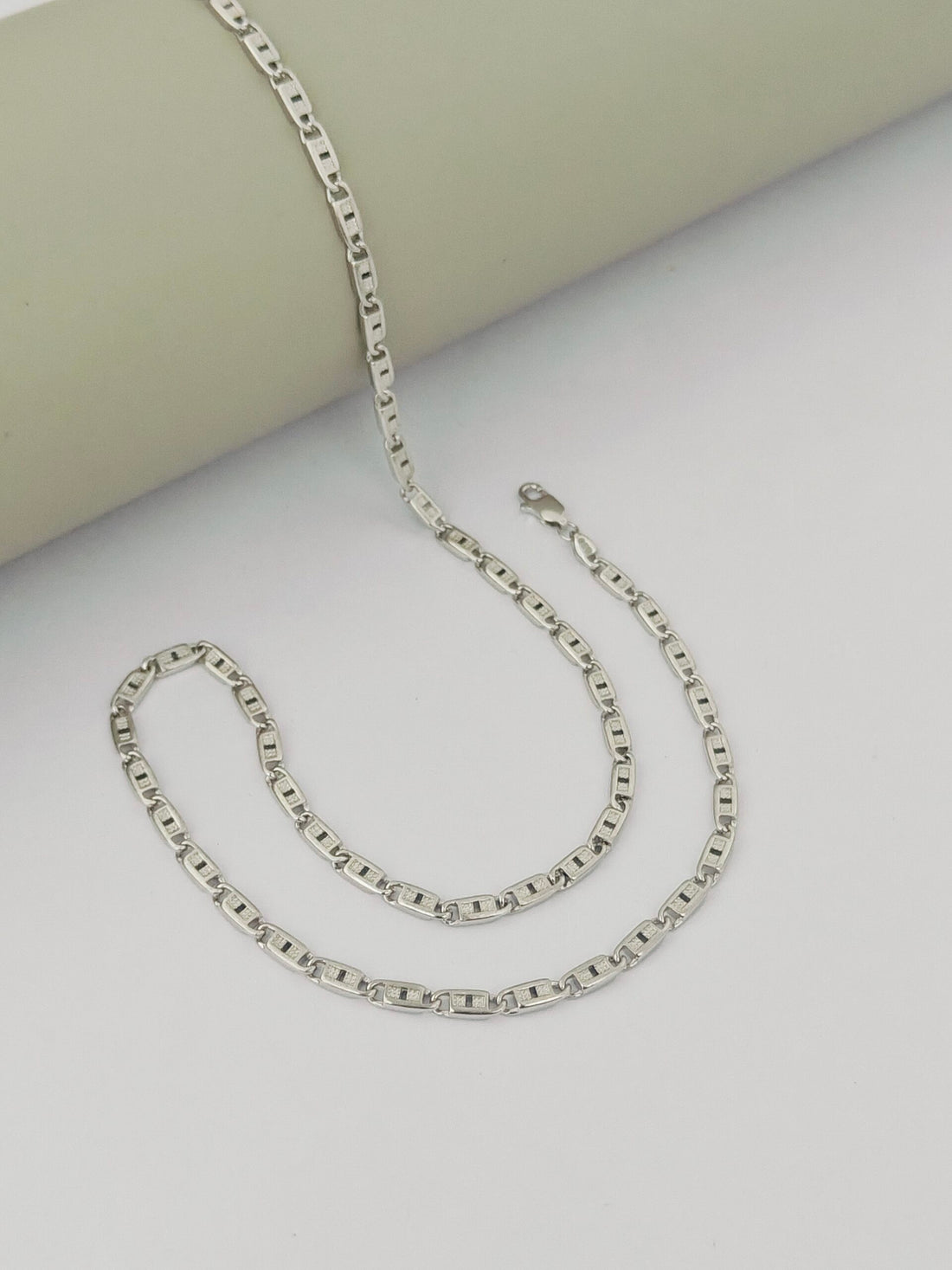 Silver chain necklace on a light gray surface