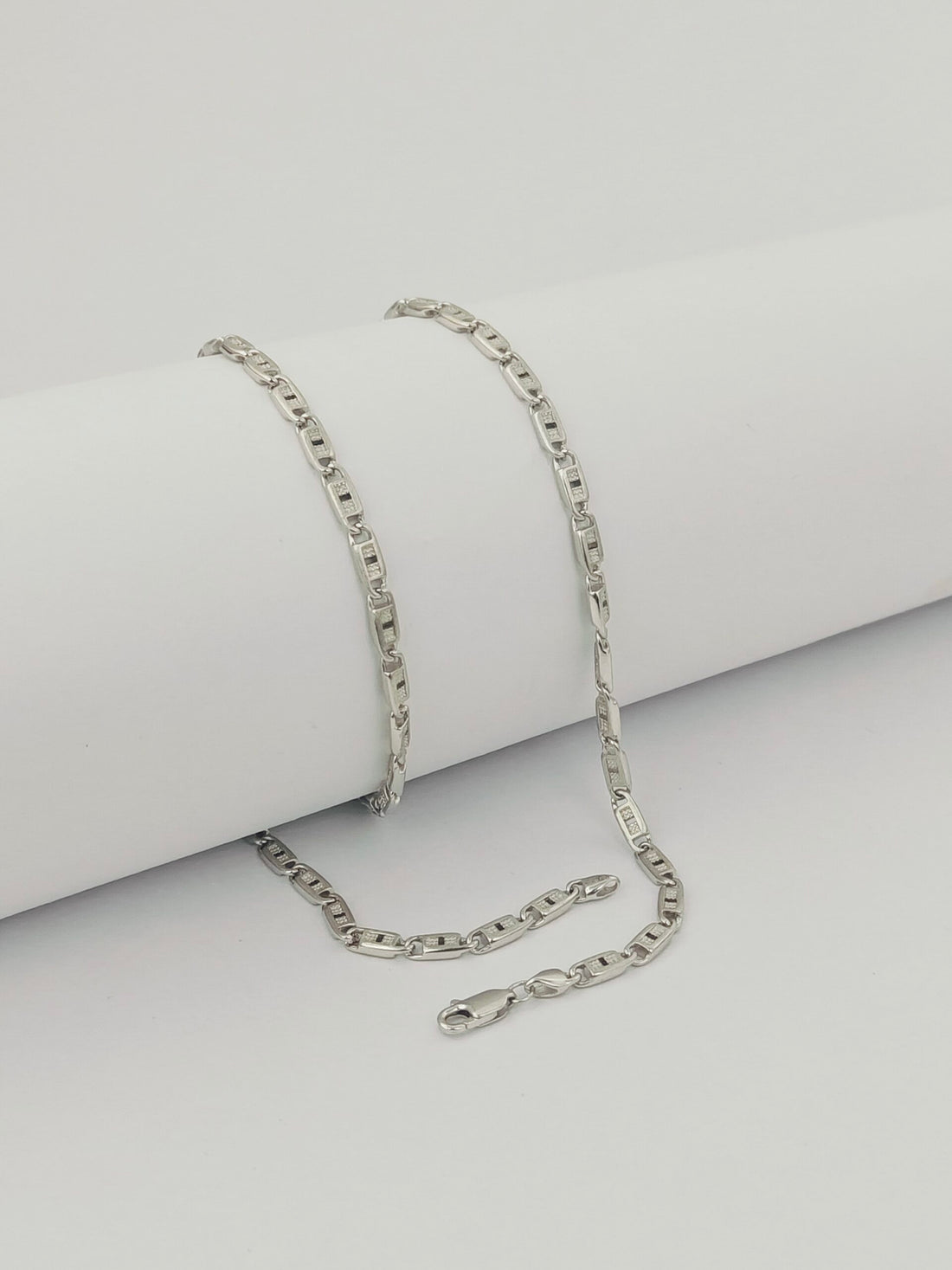 Silver chain necklace on a light gray background