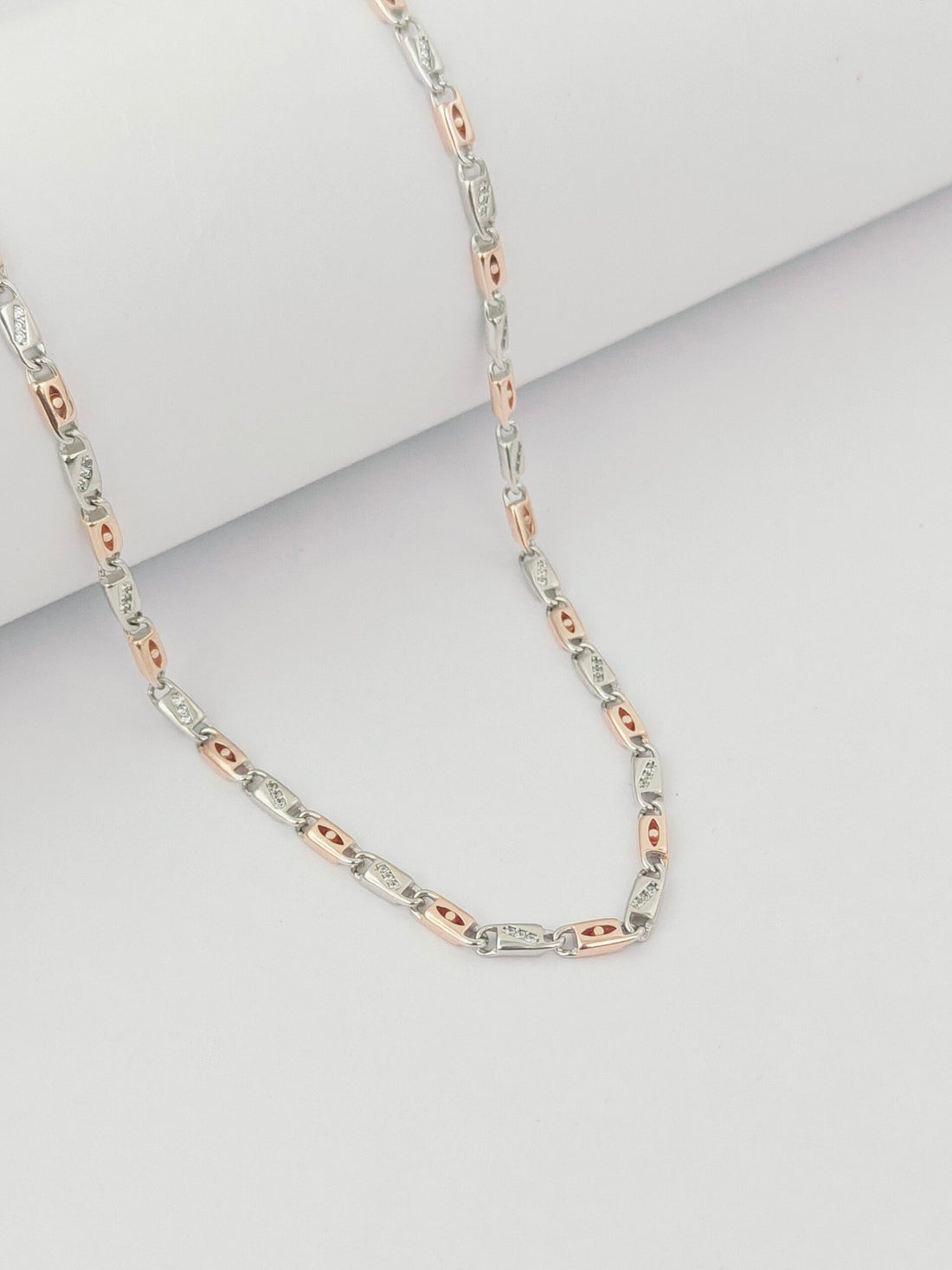 Two-tone silver and rose gold chain necklace on a light gray background