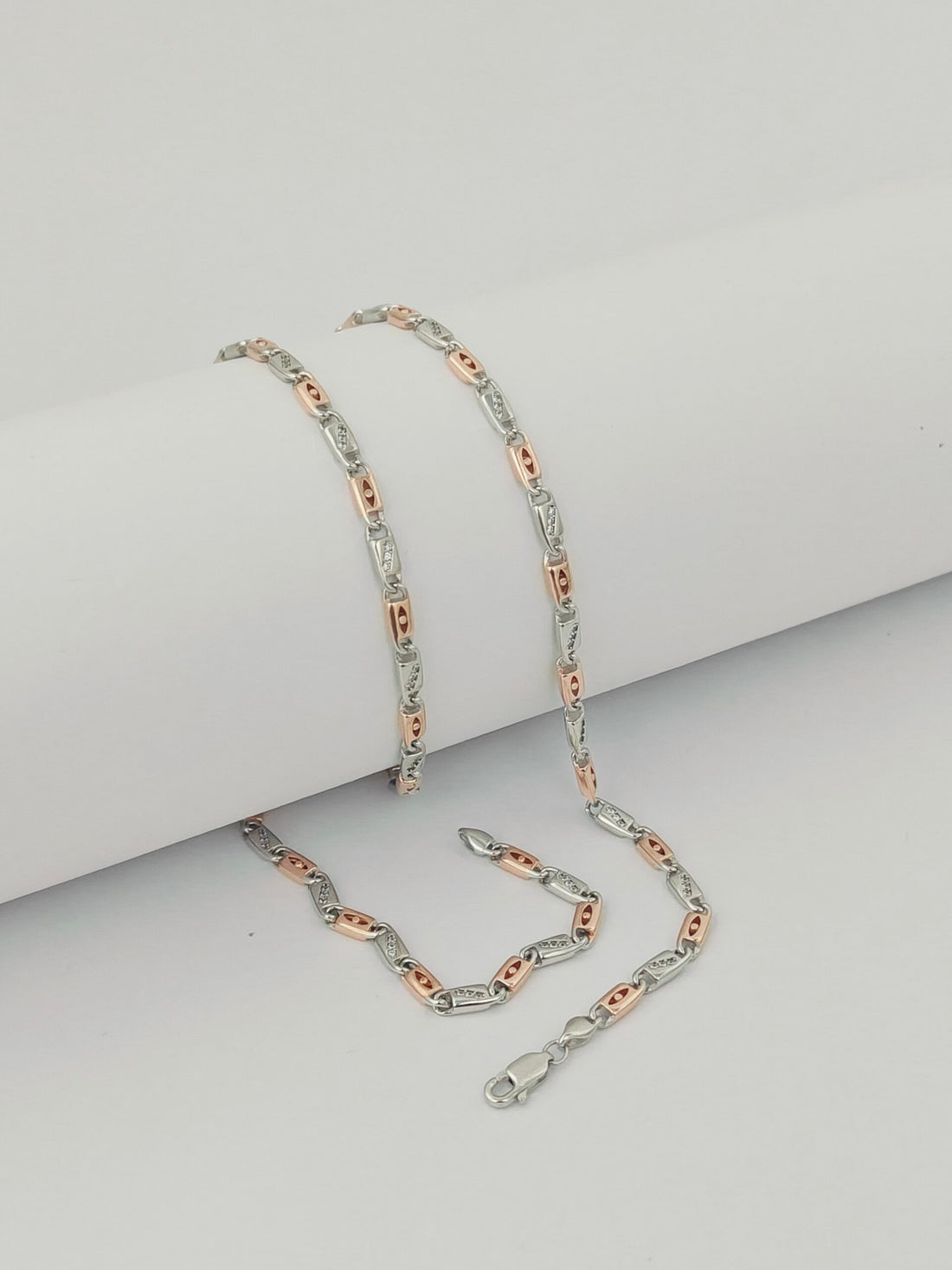 Two silver chains with rose gold accents on a light gray background