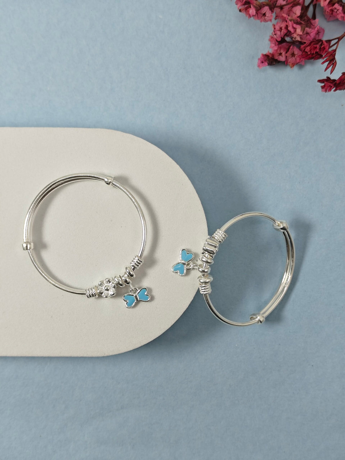 Silver hoop earrings with butterfly charms on a light blue background