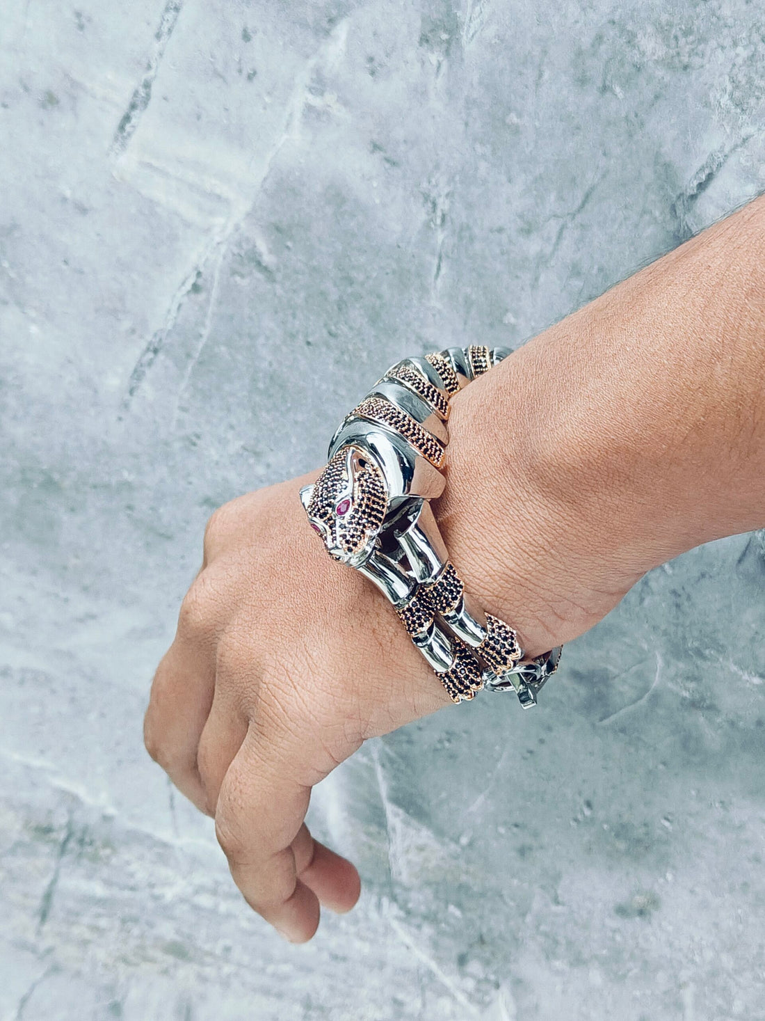 Hand wearing multiple silver bracelets on a marble background