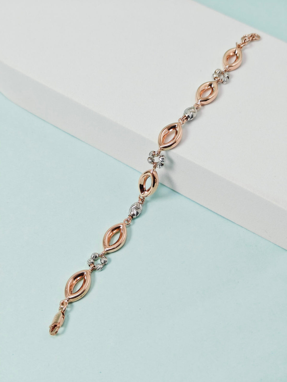 Rose gold and silver bracelet on a light blue background
