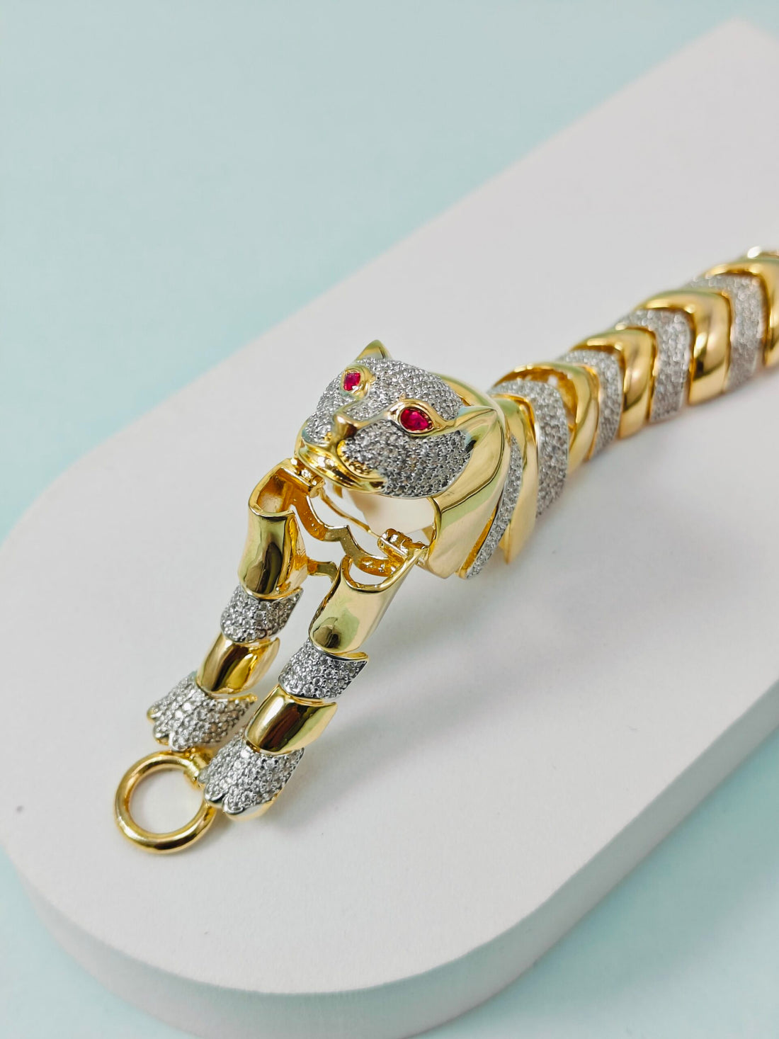 Gold panther bracelet with gemstones on a light blue background