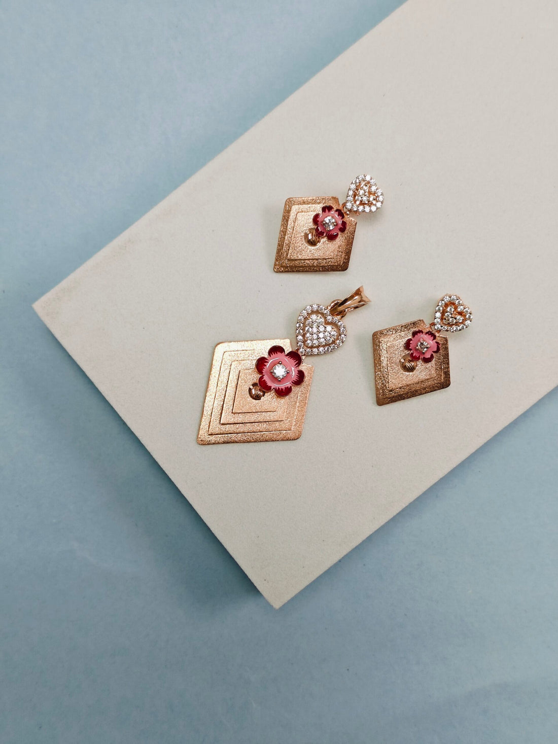 Set of gold earrings with floral designs on a light gray surface.