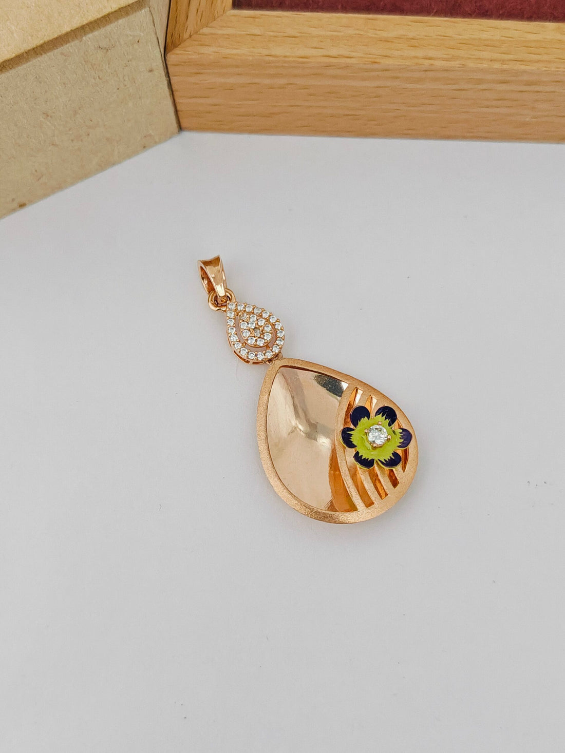 Gold pendant with floral design on a light gray surface