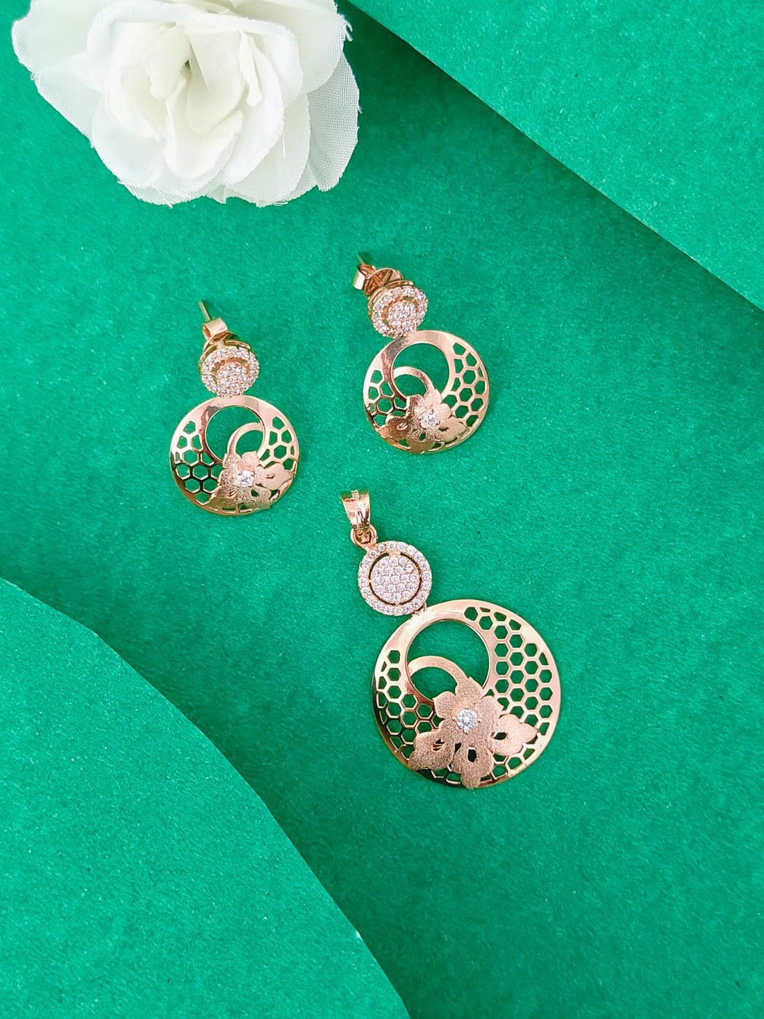Gold jewelry set with pendant and earrings on a green background