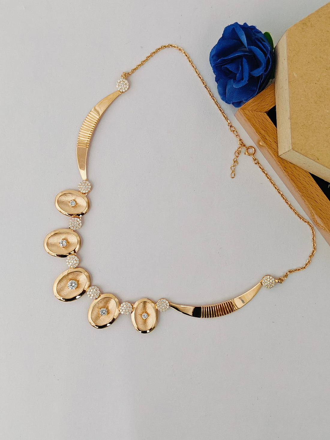 Gold necklace with decorative elements on a light gray background