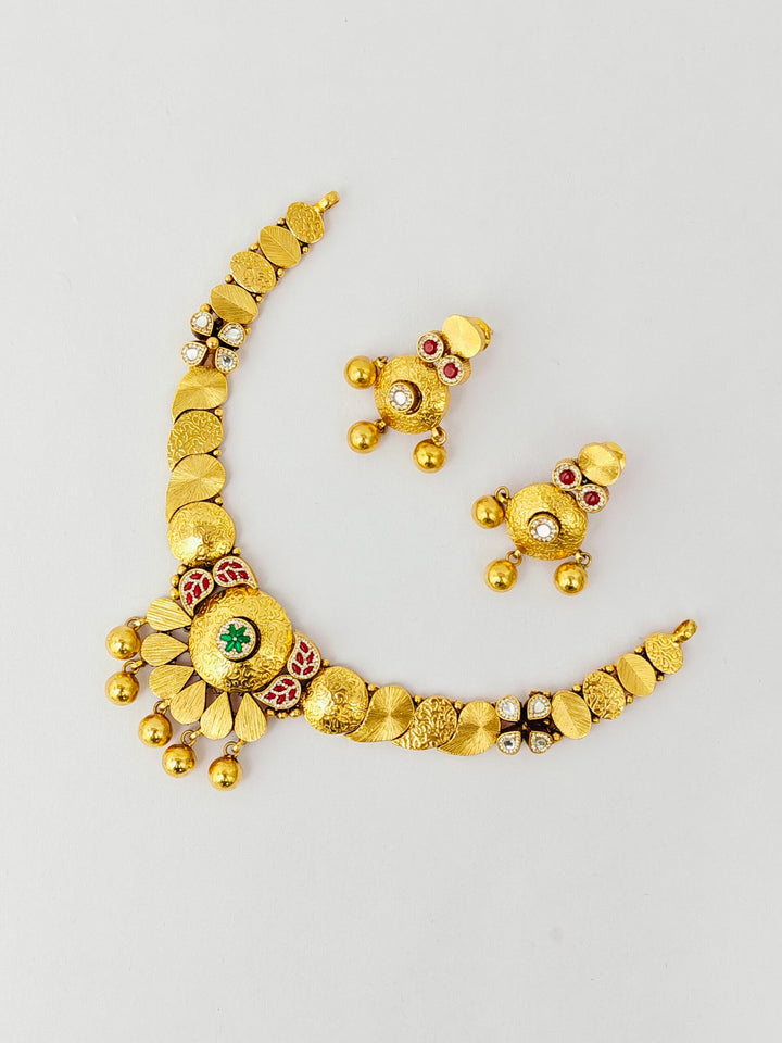 Gold necklace and earrings set on a light gray background