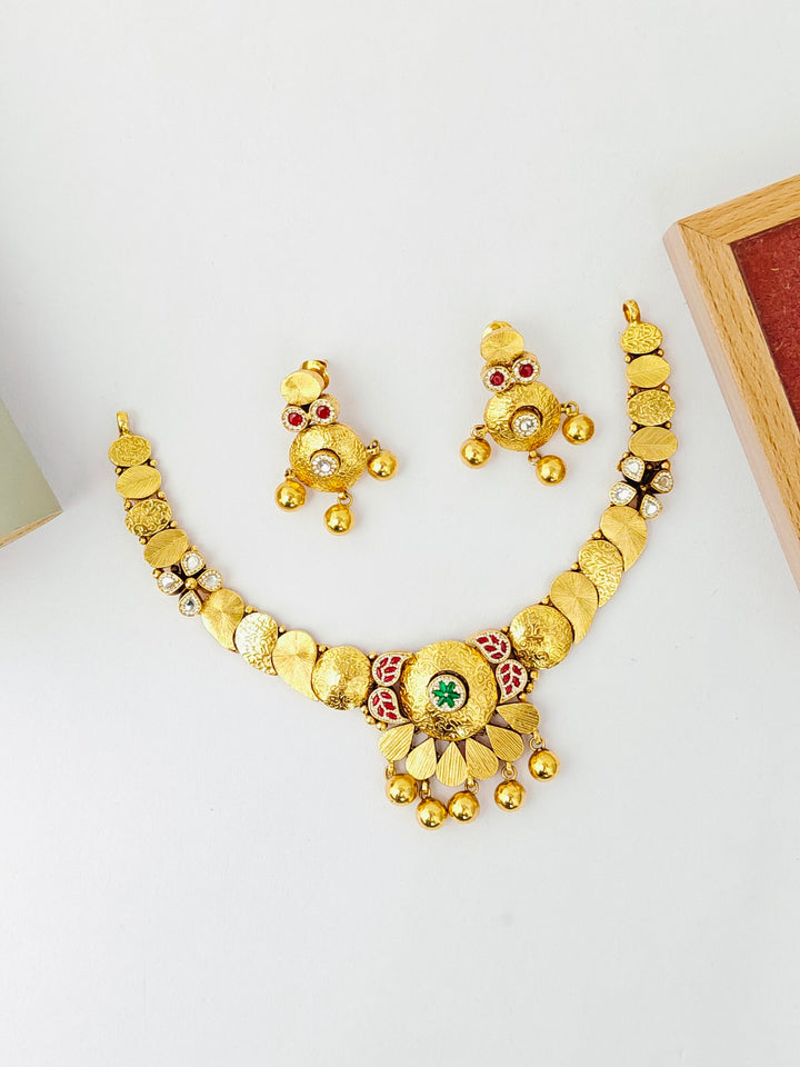 Gold necklace and earrings set on a white surface
