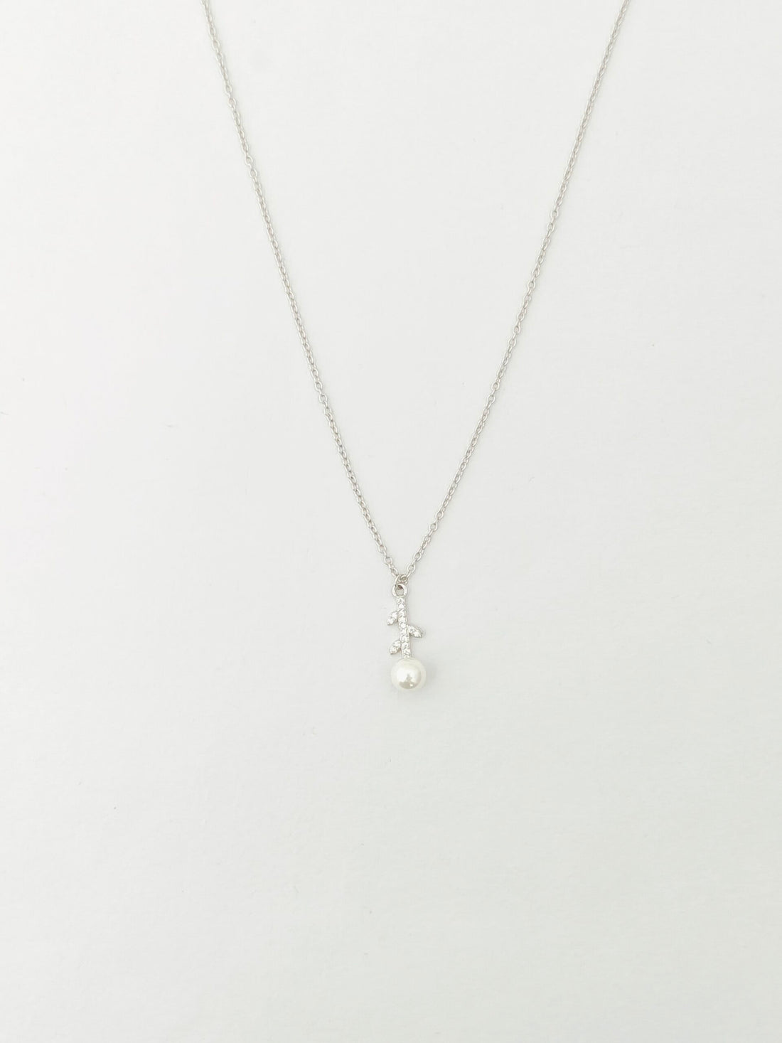 Pearl necklace on a thin chain against a white background