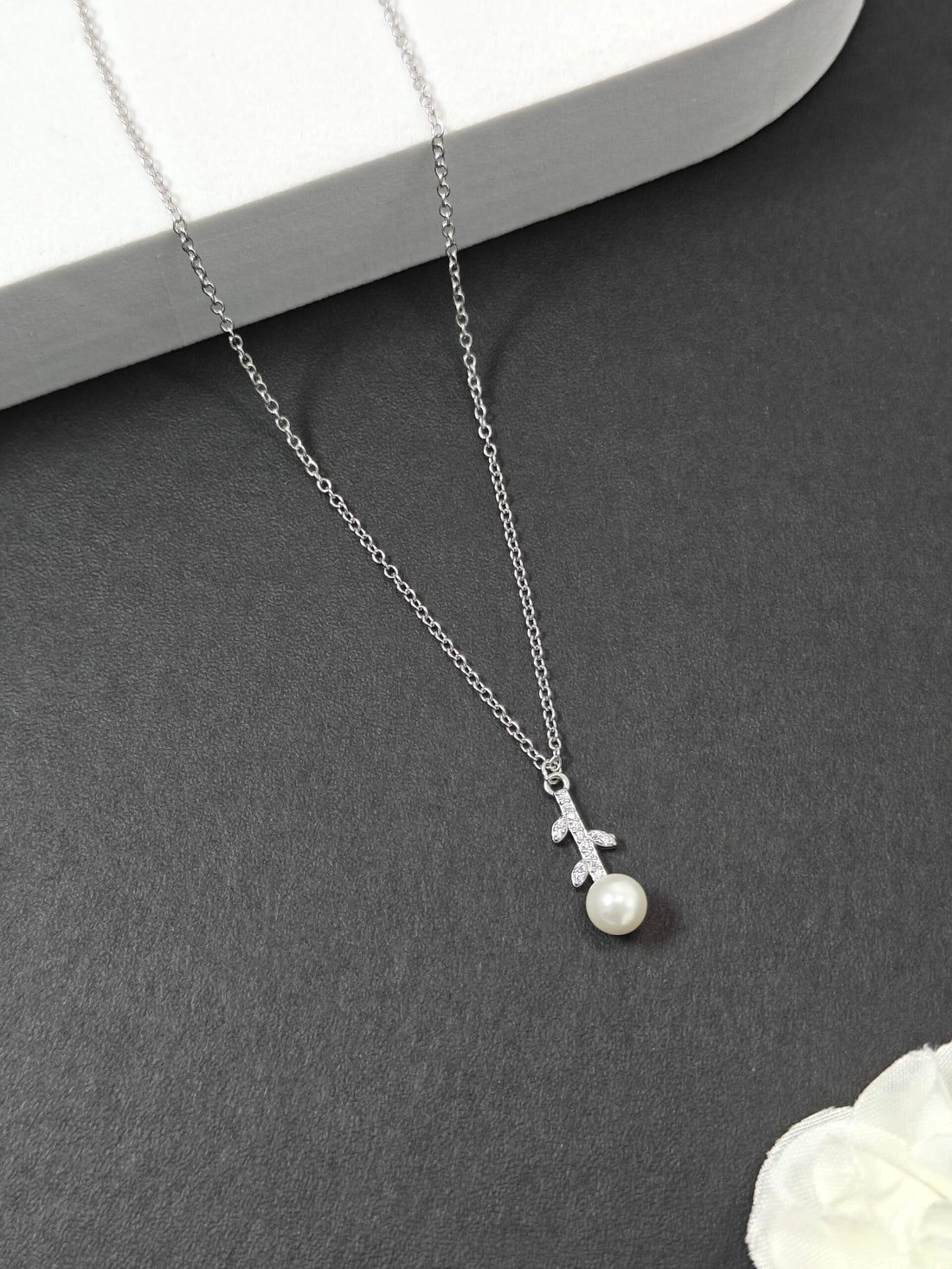 Silver necklace with a small pearl pendant on a gray surface