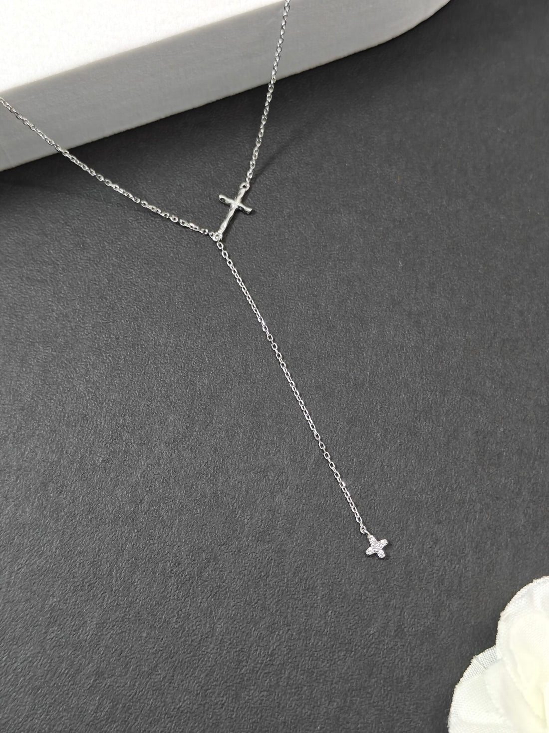 Silver necklace with cross pendants on a gray surface