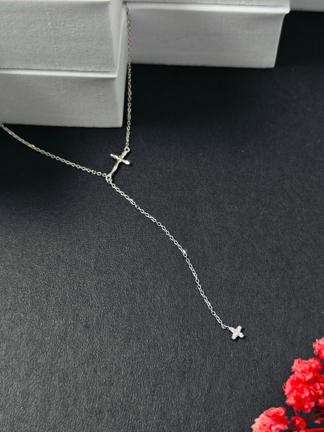 Silver necklace with cross pendants on a dark surface