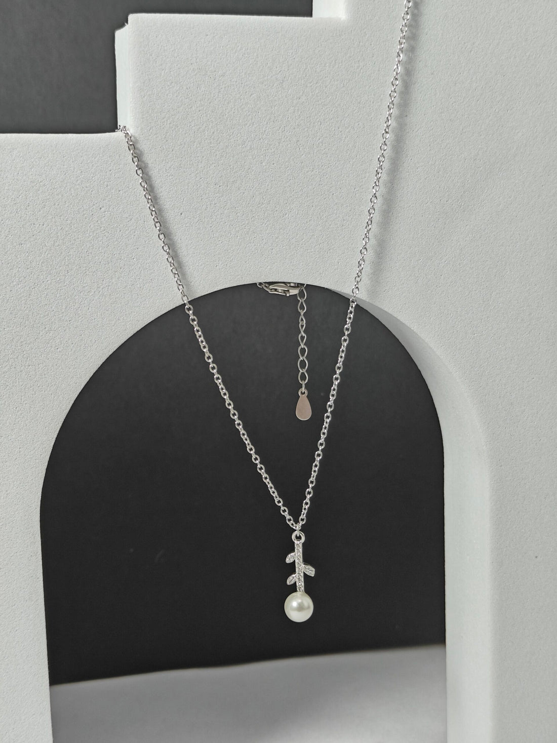 Silver necklace with a pendant on a gray stand