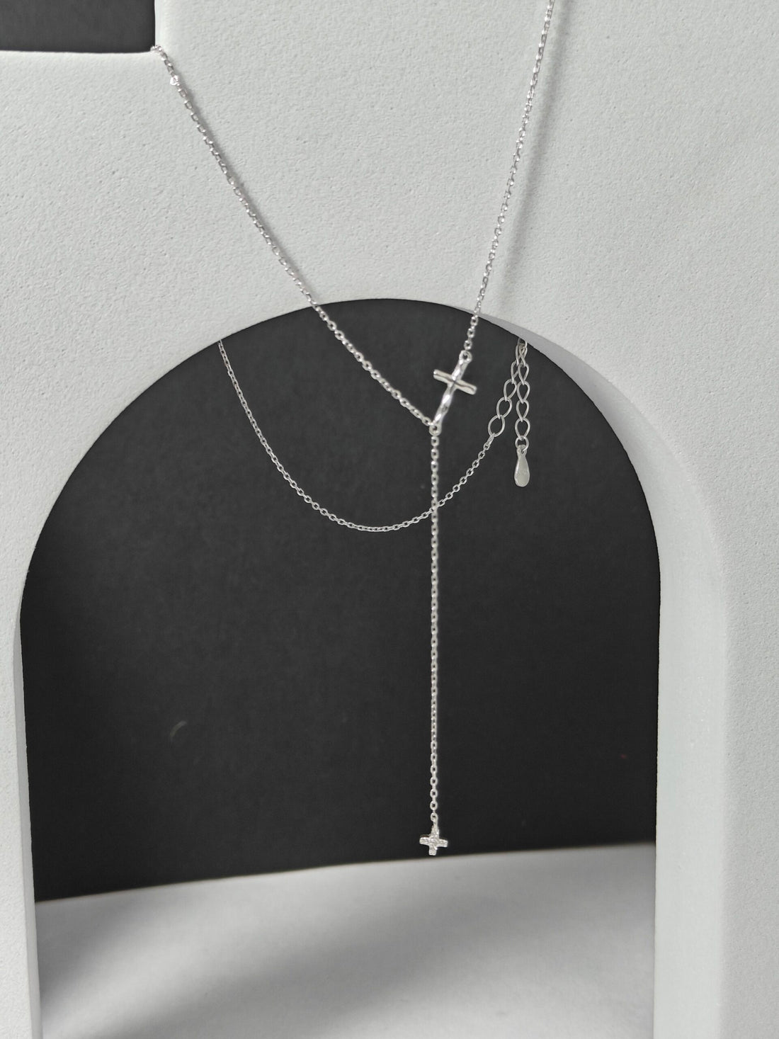 Silver necklace with cross pendants on a gray background
