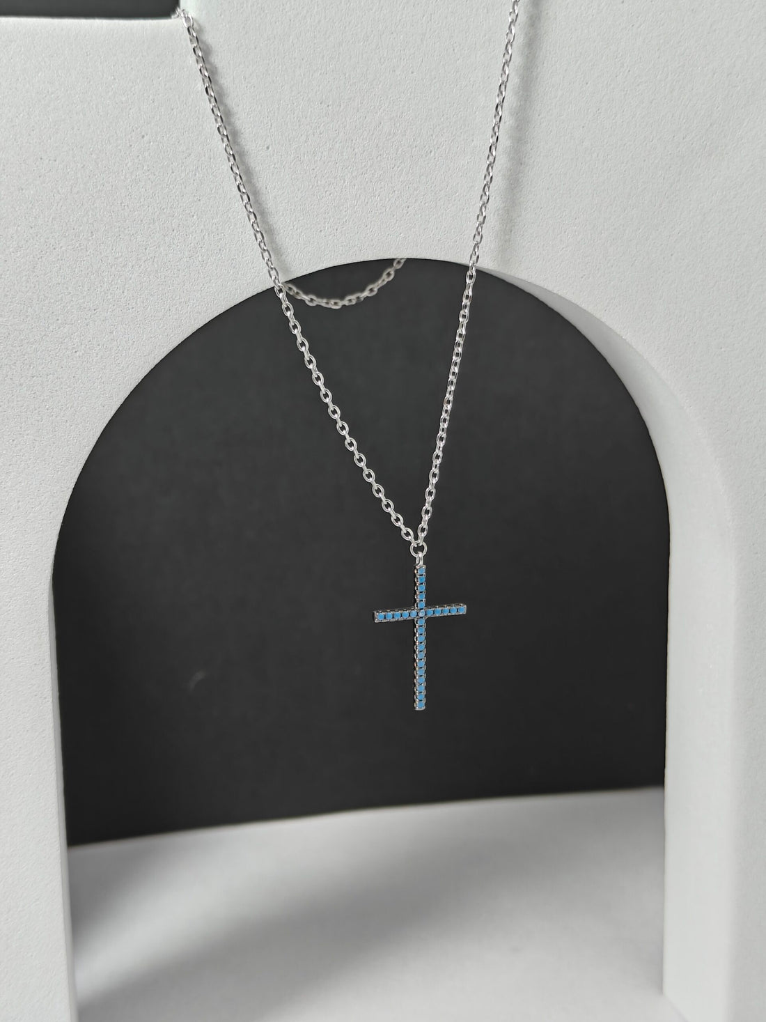 Silver cross necklace on a black and white background