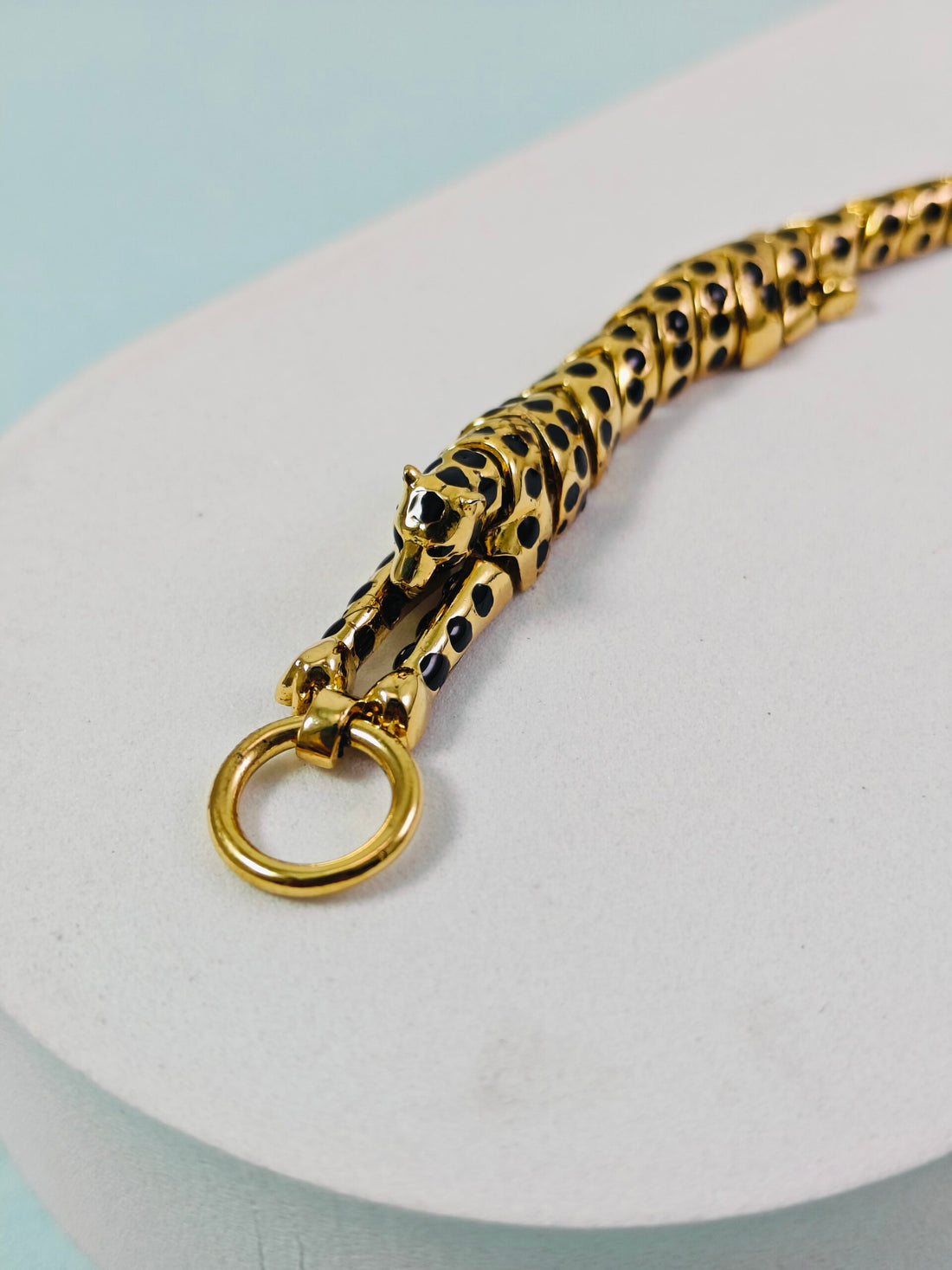 Gold and black panther keychain on a light blue background