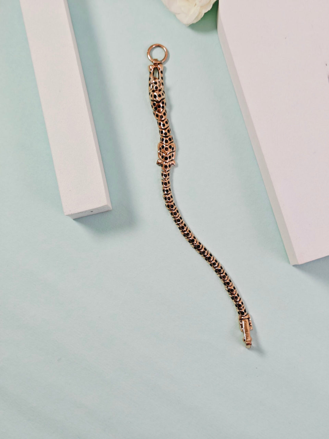Gold chain bracelet on a light blue background