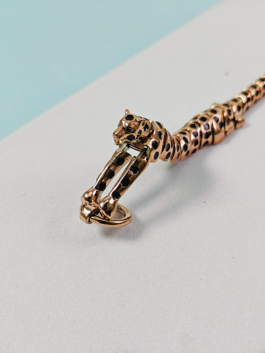 Gold bracelet with a panther design on a light gray surface