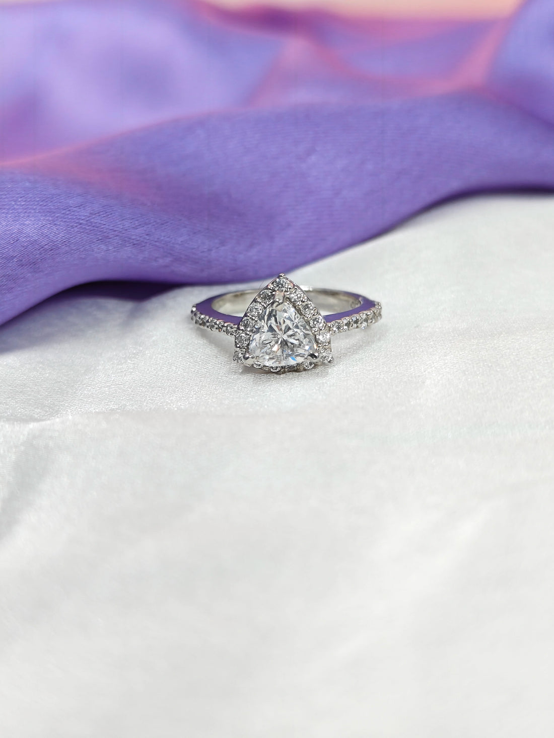 Diamond ring on a white surface with a purple fabric background