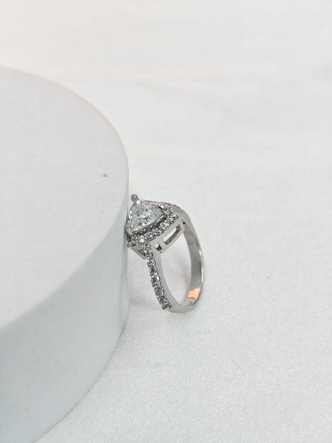 Silver ring with a diamond on a white surface