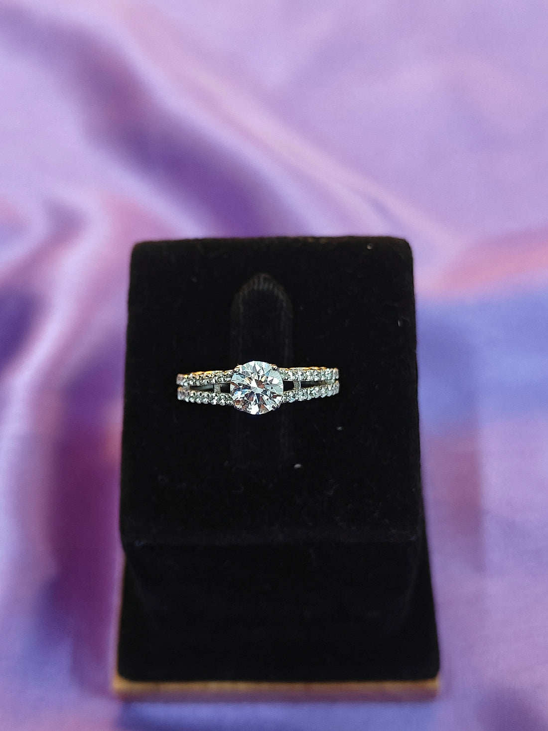 Diamond ring on a black velvet stand with a purple fabric background