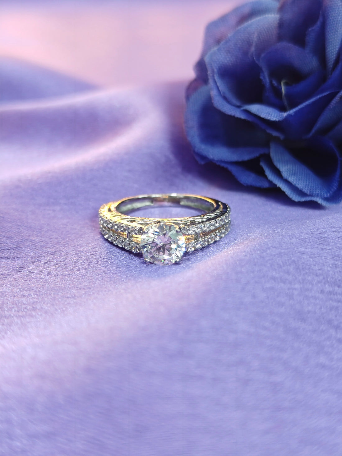 Diamond ring on a purple fabric background with a blue rose