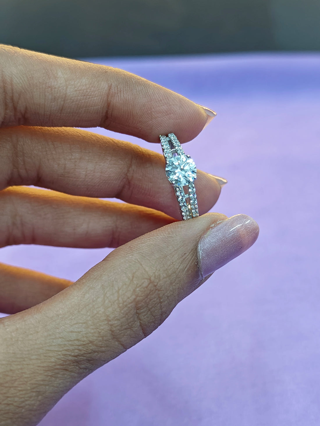 Hand wearing a diamond ring with a blurred background