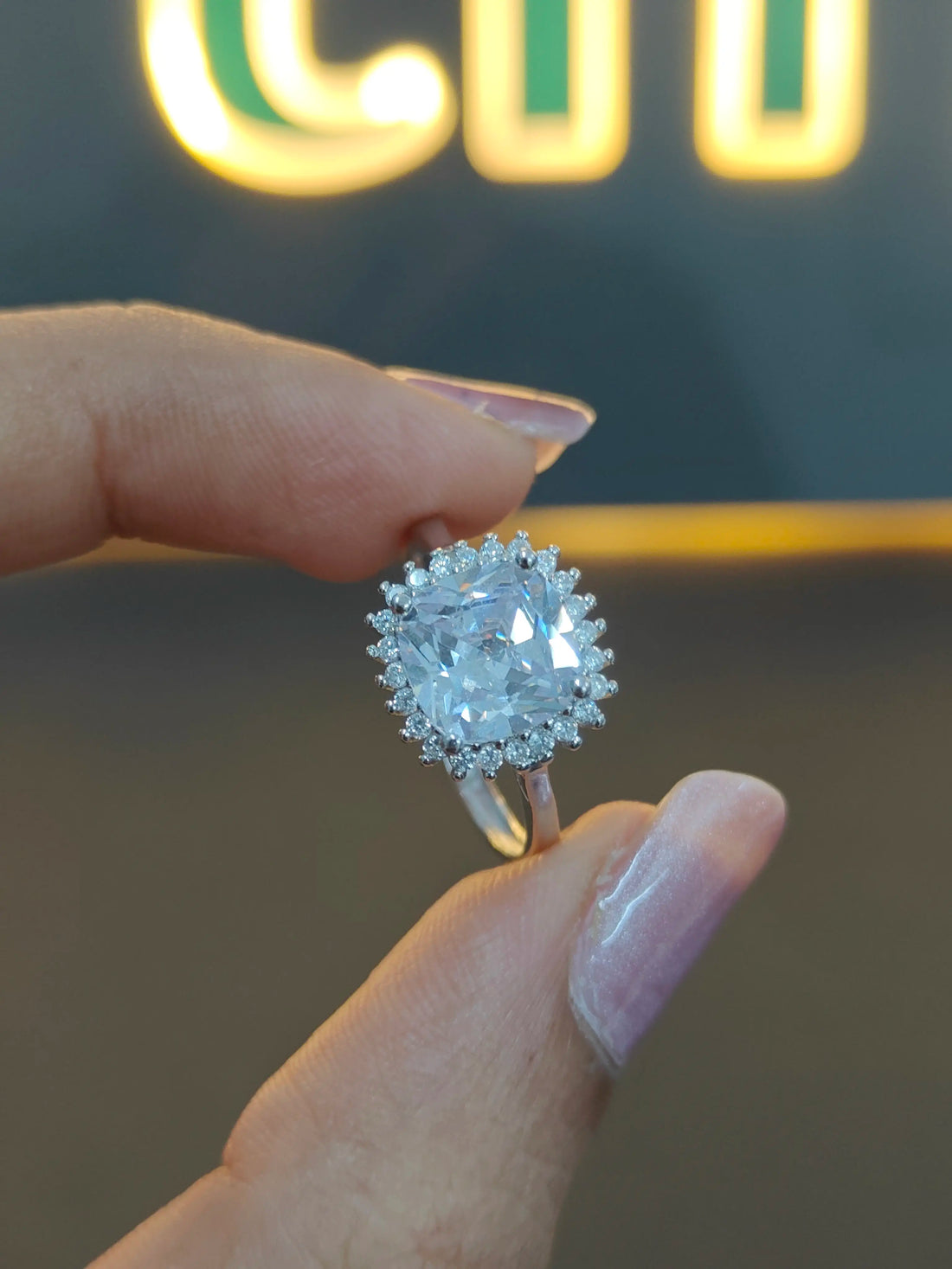 Diamond ring held by a hand with a blurred background