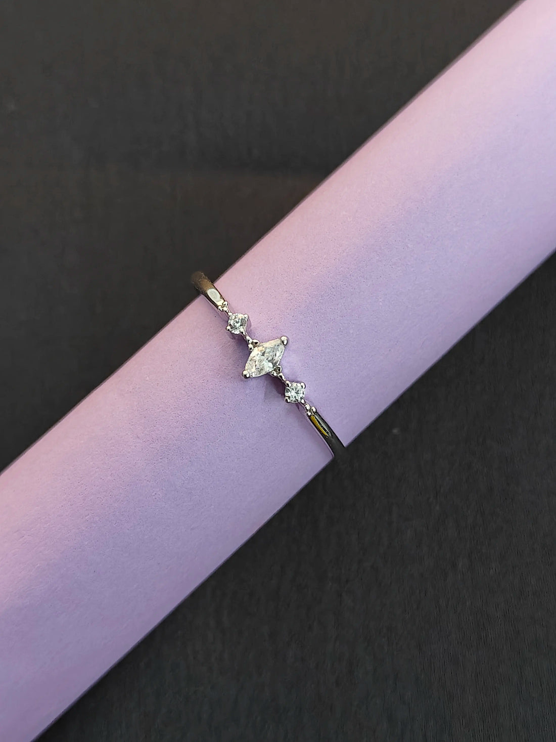 Delicate ring with a heart-shaped gemstone on a purple and black background