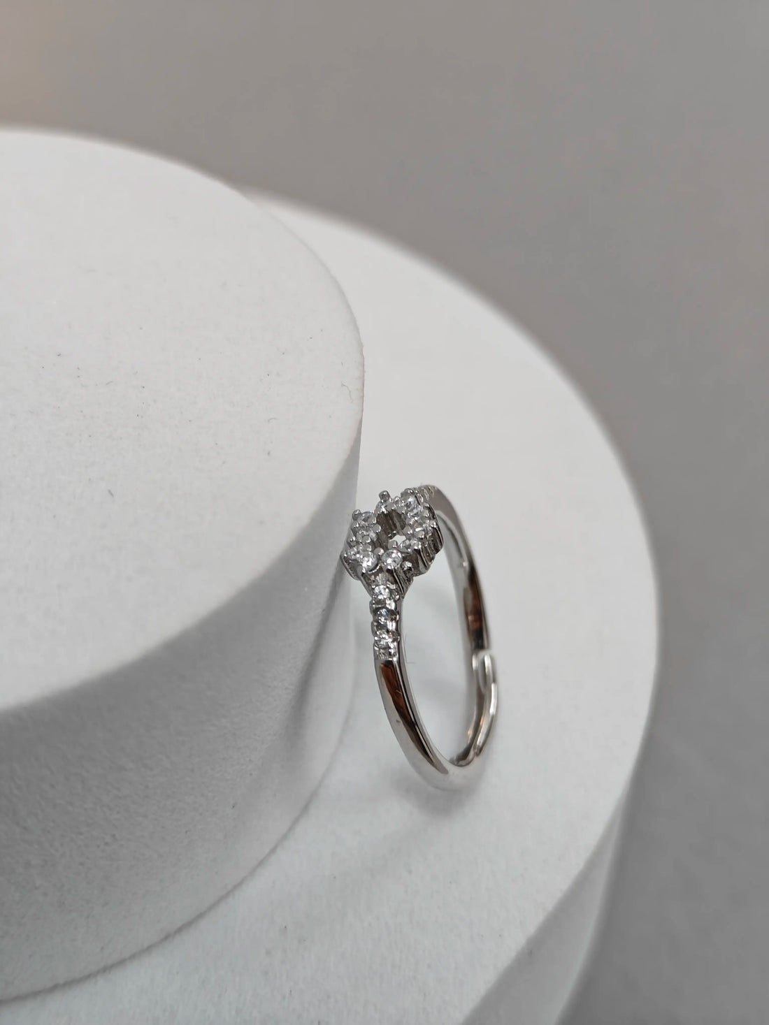 Diamond ring on a white stand with a gray background