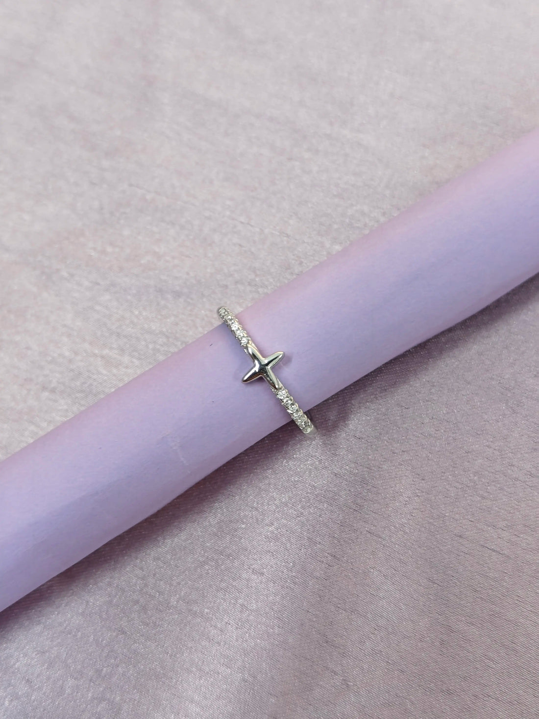 Silver ring with a star design on a pink surface