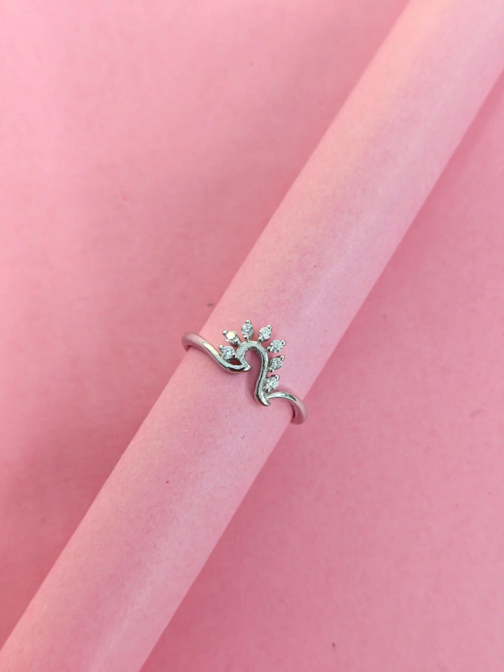 Silver ring with small stones on a pink background