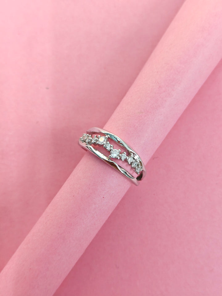 Silver ring with small diamonds on a pink fabric background