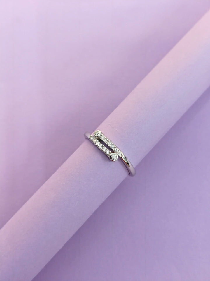 Silver ring with small diamonds on a light purple background