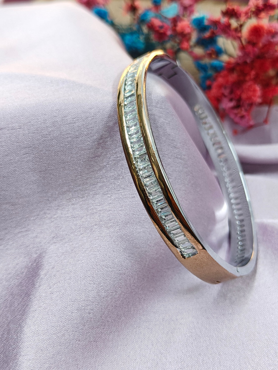 Gold ring with gemstones on a light pink fabric background