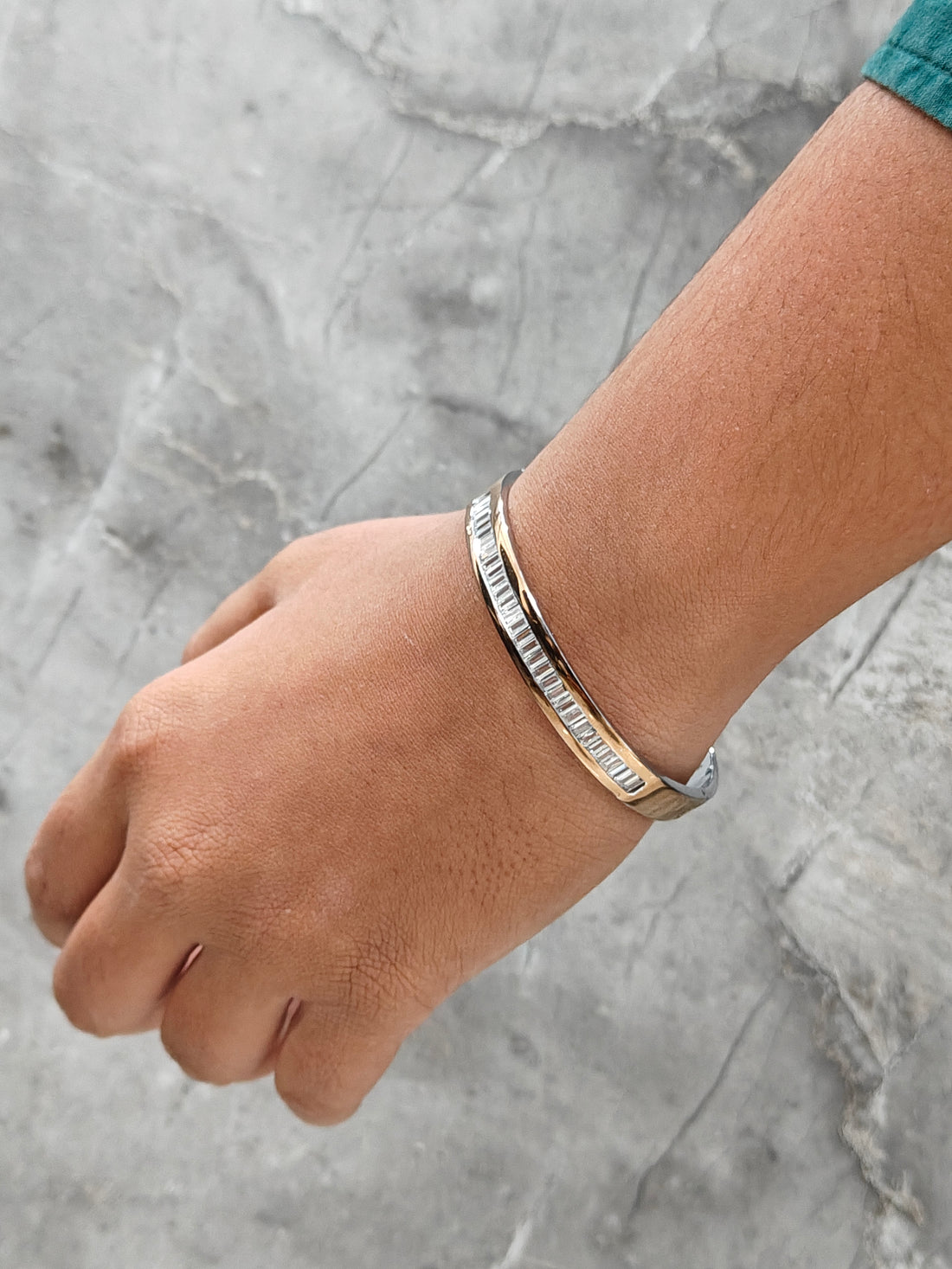 Hand wearing a bracelet on a gray marble surface