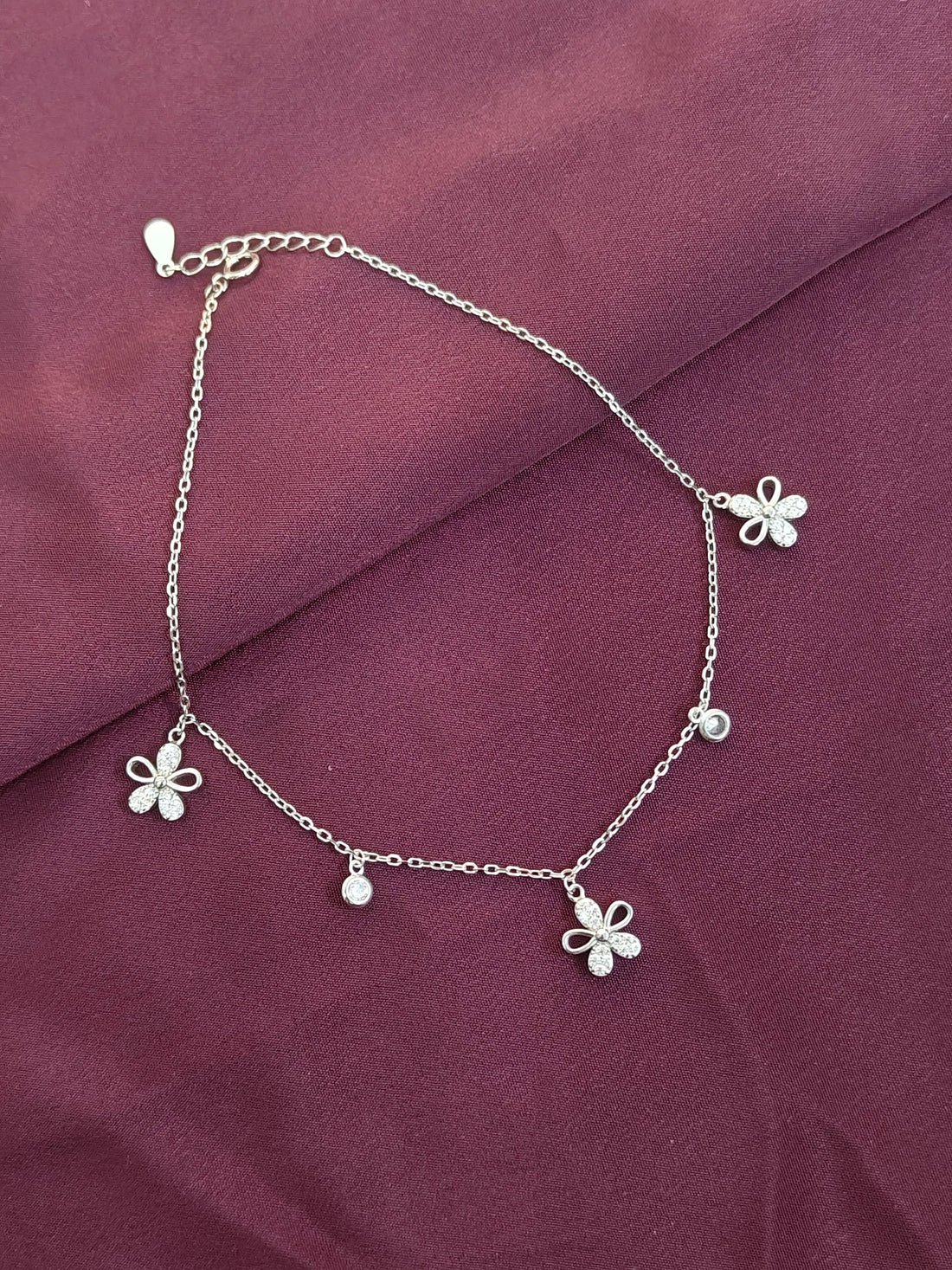 Silver anklet with butterfly charms on a purple fabric background