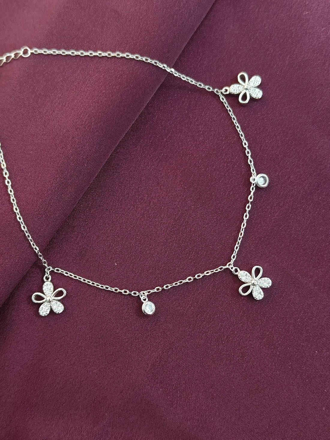 Silver anklet with butterfly charms on a purple fabric background