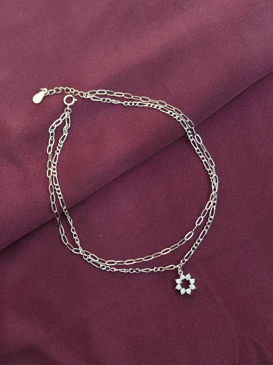 Silver chain bracelet with a star-shaped charm on a purple fabric background