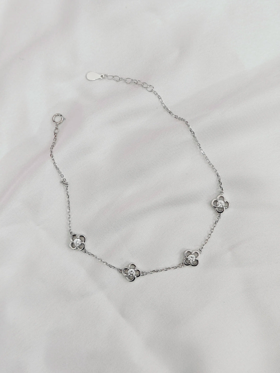 Silver bracelet with floral designs on a light gray background