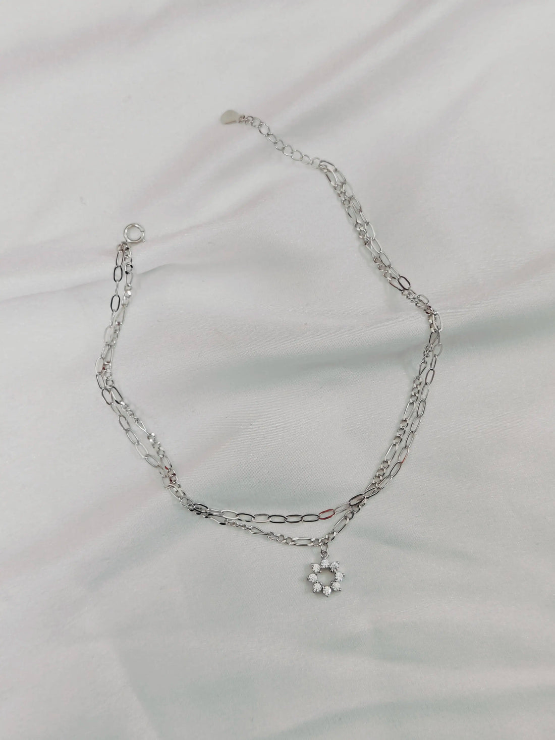 Silver chain necklace on a light gray fabric background