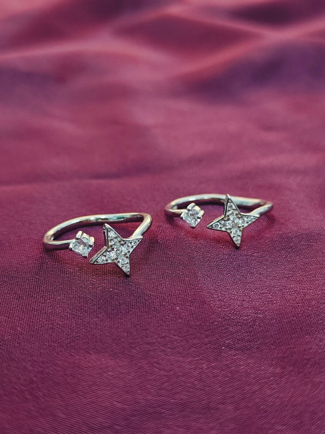 Star-shaped silver earrings on a purple fabric background