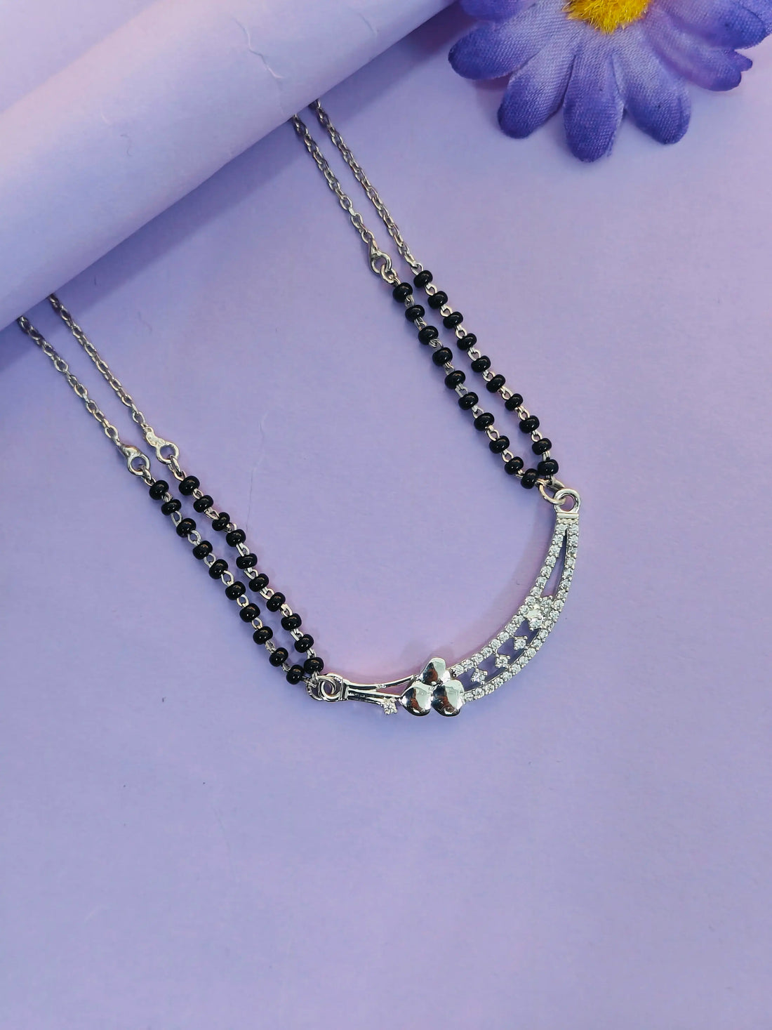 Necklace with black beads and silver clasp on a purple background
