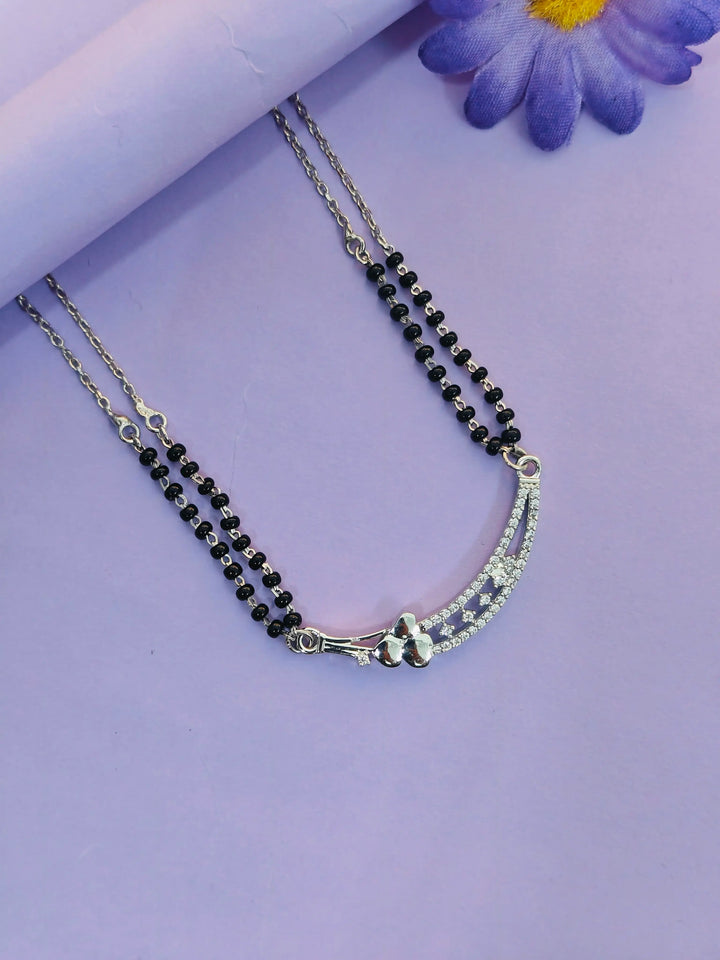 Necklace with black beads and silver clasp on a purple background
