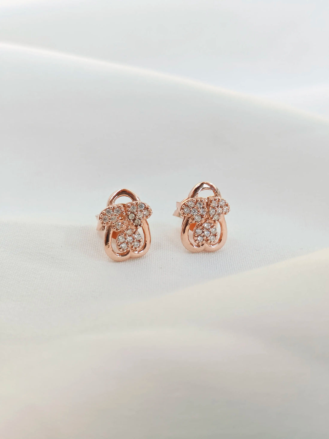 Rose gold earrings with diamond accents on a light background