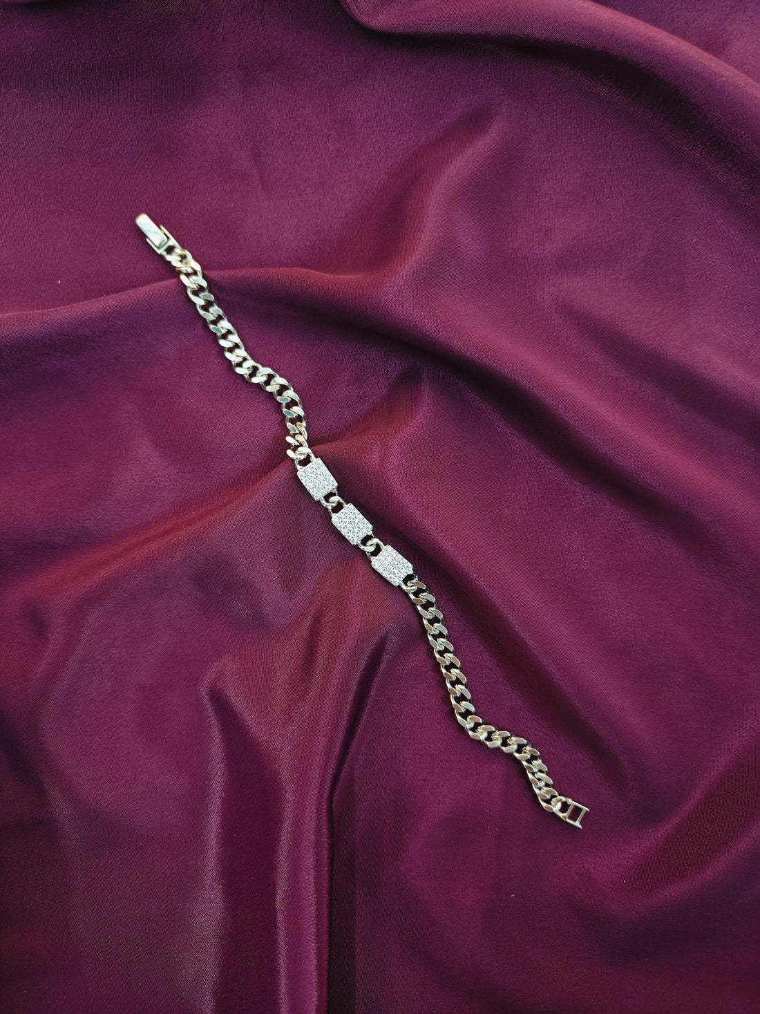 Silver chain bracelet on a purple fabric background