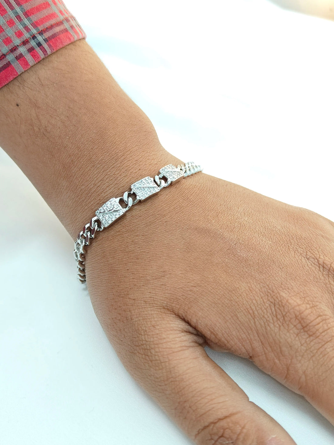 Silver bracelet on a wrist with a plain background