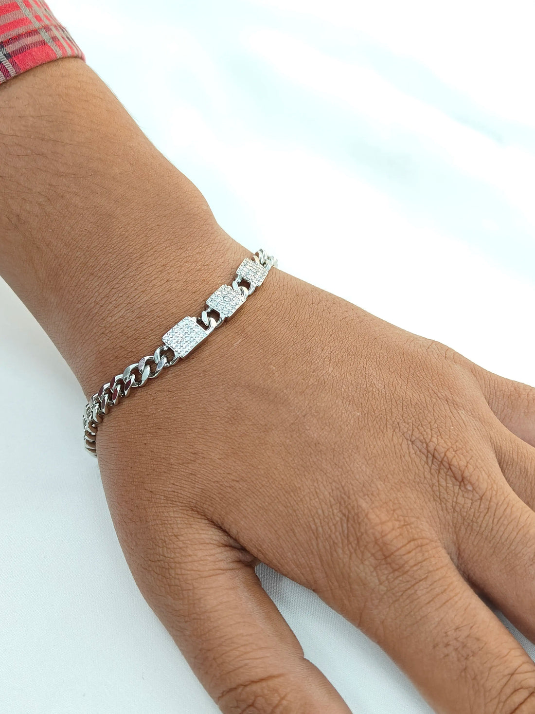 Silver bracelet on a wrist against a light background